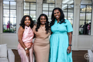 Photo of three African- American women smile and pose together at an elegant event venue