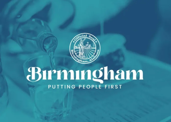 A person pouring a clear liquid into a glass of ice, with a blue color overlay featuring the official seal of Birmingham, Alabama, and the text "Birmingham: Putting People First."