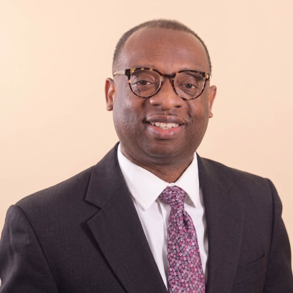 Professional headshot of Walter Goss III wearing a suit and purple tie.